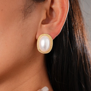 Vintage oval pearl earrings with gold textured metal borders worn by a female model