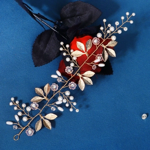 Close-up of gold wire bridal headband with white pearls, crystals, and metal leaves