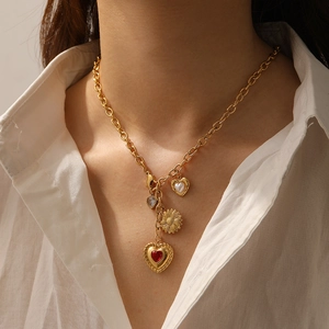Detailed close-up of multi-pendant gold-plated necklace with red gem and sunflower