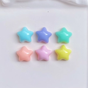 Flat lay of colorful resin mini stars in pastel shades on a white textured tray