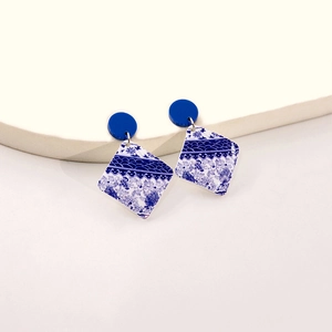 Detail of square blue and white porcelain pattern earrings with a geometric acrylic design