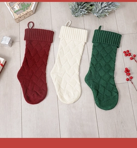 Detailed cable knit Christmas stockings in red, white and green on rustic wood floor