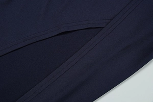 Macro view of navy blue dress fabric featuring neat double-needle stitching and side slit detail