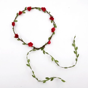 Detail of bridal floral headband with red silk roses and green leaves on white background