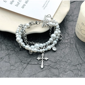Vue macro du bracelet perles Y2K multicouches avec grand pendentif croix gothique et strass