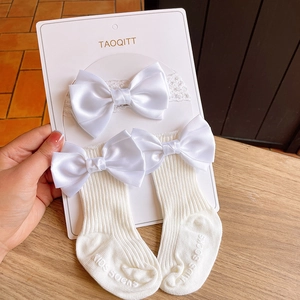 Detailed view of baby lace headband and ribbed socks set with large satin bows