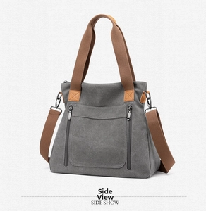 Side view of grey canvas tote bag with brown straps and dual vertical zipper pockets