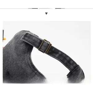 Detailed view of the adjustable bronze metal buckle on a black washed denim baseball cap