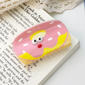 Pink donut hair claw clip with cream frosting and cute eyes on vintage book page