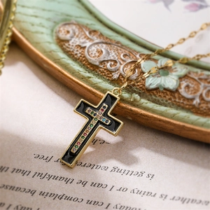 Detail of vintage gold cross pendant with black enamel and multi-colored rhinestones