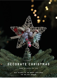 Close-up of golden Christmas tree topper star with tartan bow, pinecone, and berries