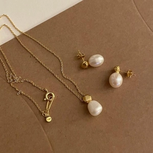 Detail of 925 sterling silver pearl jewelry set showing necklace and earrings in gold finish