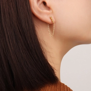 Boucles d'oreilles spirale en U dorées avec longue chaîne sur un mannequin femme