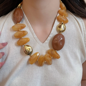Close-up of amber and brown acrylic resin beads with gold accents on a fashion necklace