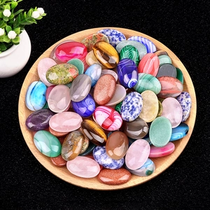 Mix of oval-shaped polished crystal and agate gemstones in a wooden tray