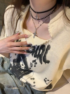 Close-up of layered cross pendant necklace with black choker on beige sweater