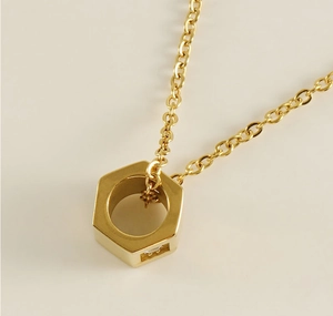 Macro shot of gold nut-shaped pendant on thin chain with detailed crystal inlay