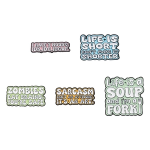 Set of five funny metal pins with sarcastic English quotes on a white background