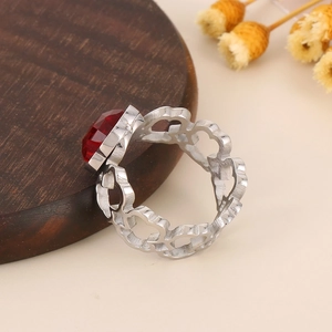 Detailed close-up of a silver floral ring featuring a ruby-red gemstone with hollow patterns