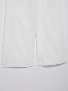 Detailed view of white linen wide-leg trousers hem showing double stitching and fabric texture