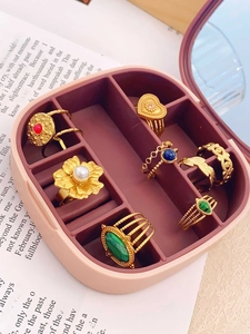 Detail view of 7 vintage gold rings with emerald and sapphire stones in a pink jewelry box