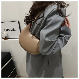 Khaki crescent moon shoulder bag shown on model with smooth faux leather texture