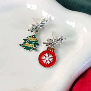 Detail von Weihnachtsbaum und Schneeflocken Ohrringen mit Emaille-Schleife auf Teller