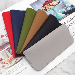 Thick leather sunglasses pouches in six colors stacked on a lifestyle magazine