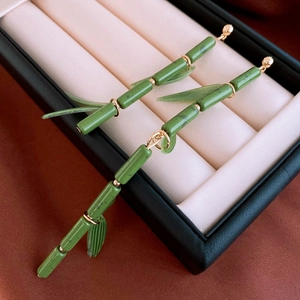 Detailed view of bamboo-shaped long earrings with green leaves in a black jewelry box
