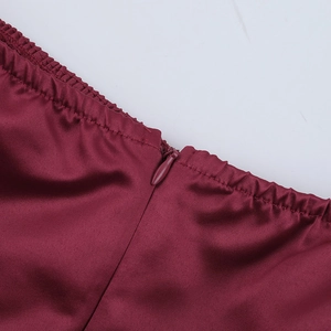 Gros plan d'une robe en satin bordeaux montrant les coutures et la fermeture éclair