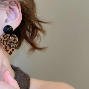 Nahaufnahme von Herz-Ohrringen mit Leopardenmuster und schwarzem Stecker am Ohr