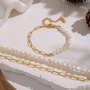 Detail of vintage gold chain necklace with natural freshwater pearls on a white stone background