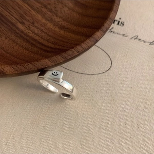 Minimalist silver smiley face open ring on beige fabric with rustic wood accents
