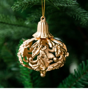 Close-up of golden hollowed leaf ornament hanging on a Christmas tree branch