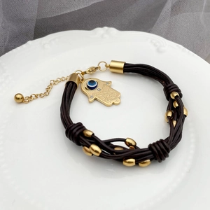 Brown braided leather bracelet featuring Hamsa pendant with blue Evil Eye charm
