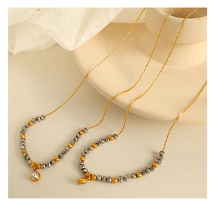 Detail of dual gold beaded necklaces with zircon pendants on elegant ceramic base