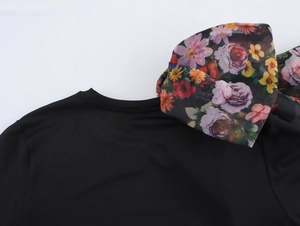 Detail of black T-shirt featuring a large floral organza bow decoration on the shoulder