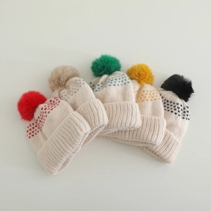 Détail de cinq bonnets tricotés pour enfants avec pompons colorés et motifs jacquard