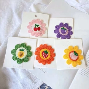 Detail view of colorful crochet flower hair clips with embroidered fruit motifs on cards