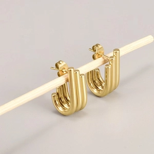 Close-up of golden triple-row C-shaped hoop earrings in 18K gold plated steel