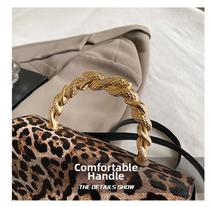 Detail of snake-shaped golden metal handles on a leopard print handbag with leather texture