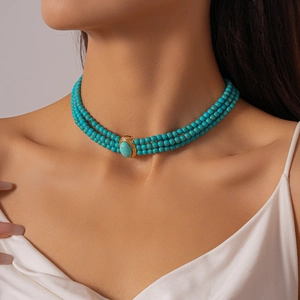 Detail of triple-layered turquoise bead choker with oval stone and gold metal trim
