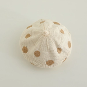 Top view of cream knitted beret with brown polka dots and detailed stitch texture
