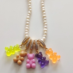Detail of colorful resin gummy bear charms and gold rings on white pearl necklace