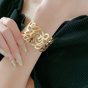 Detailed view of a wide gold cutout cuff bracelet with an abstract curved pattern