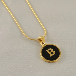 Vue macro du pendentif lettre B doré avec émail noir sur une chaîne serpent plate