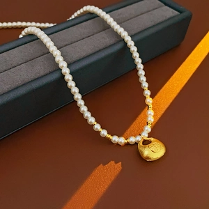 Detailed view of pearl necklace with gold lucky pouch pendant and Fu character engraving