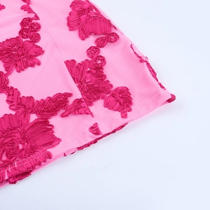 Détail macro de broderies florales rose fuchsia sur maille fine avec coutures précises