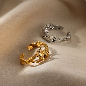 Detail of liquid metal style open rings in gold and silver on beige silk fabric