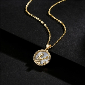 Macro shot of 18k gold plated Aquarius zodiac pendant with zircon and mother of pearl